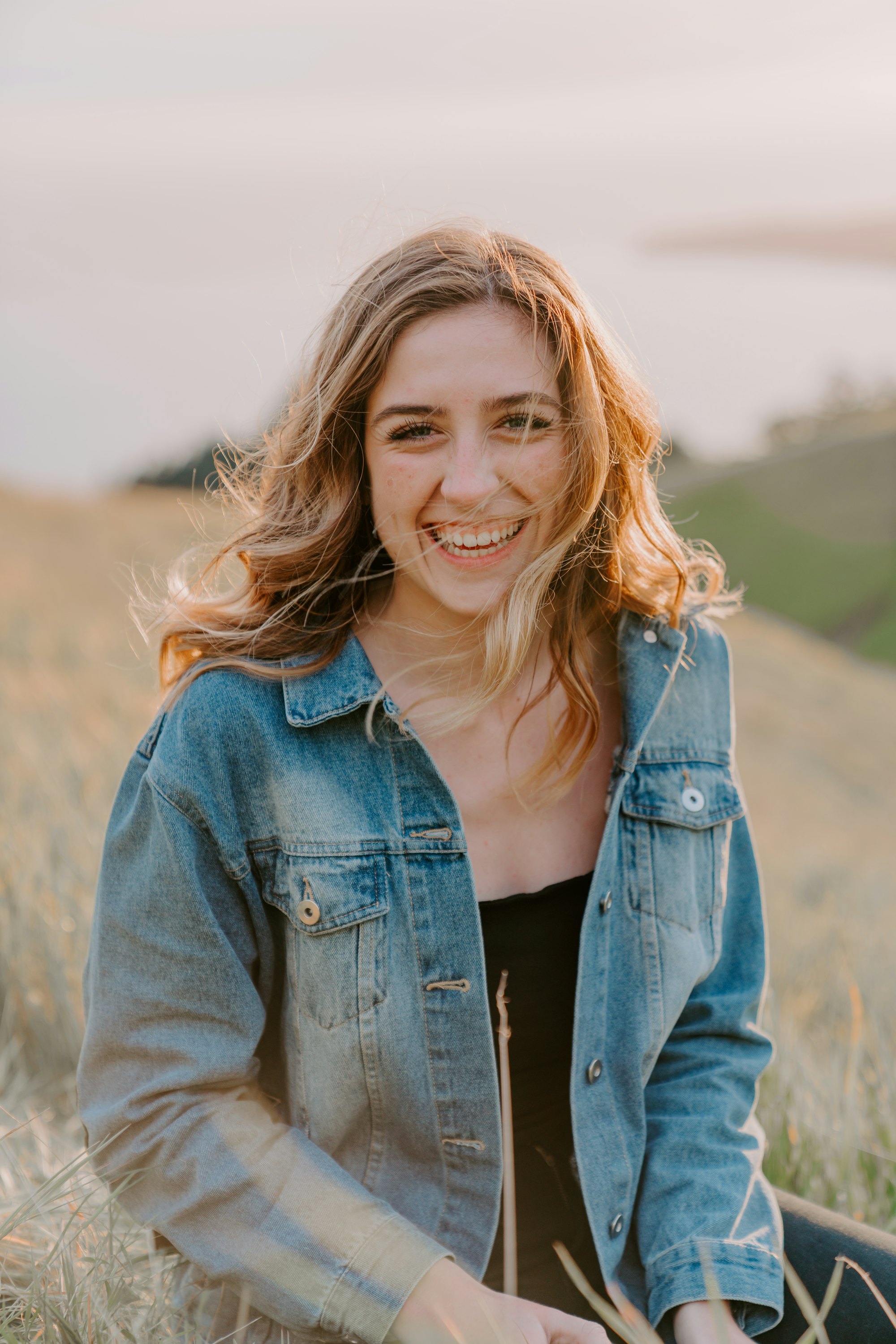 Une femme souriante dans un champ, au soleil de fin de journée
